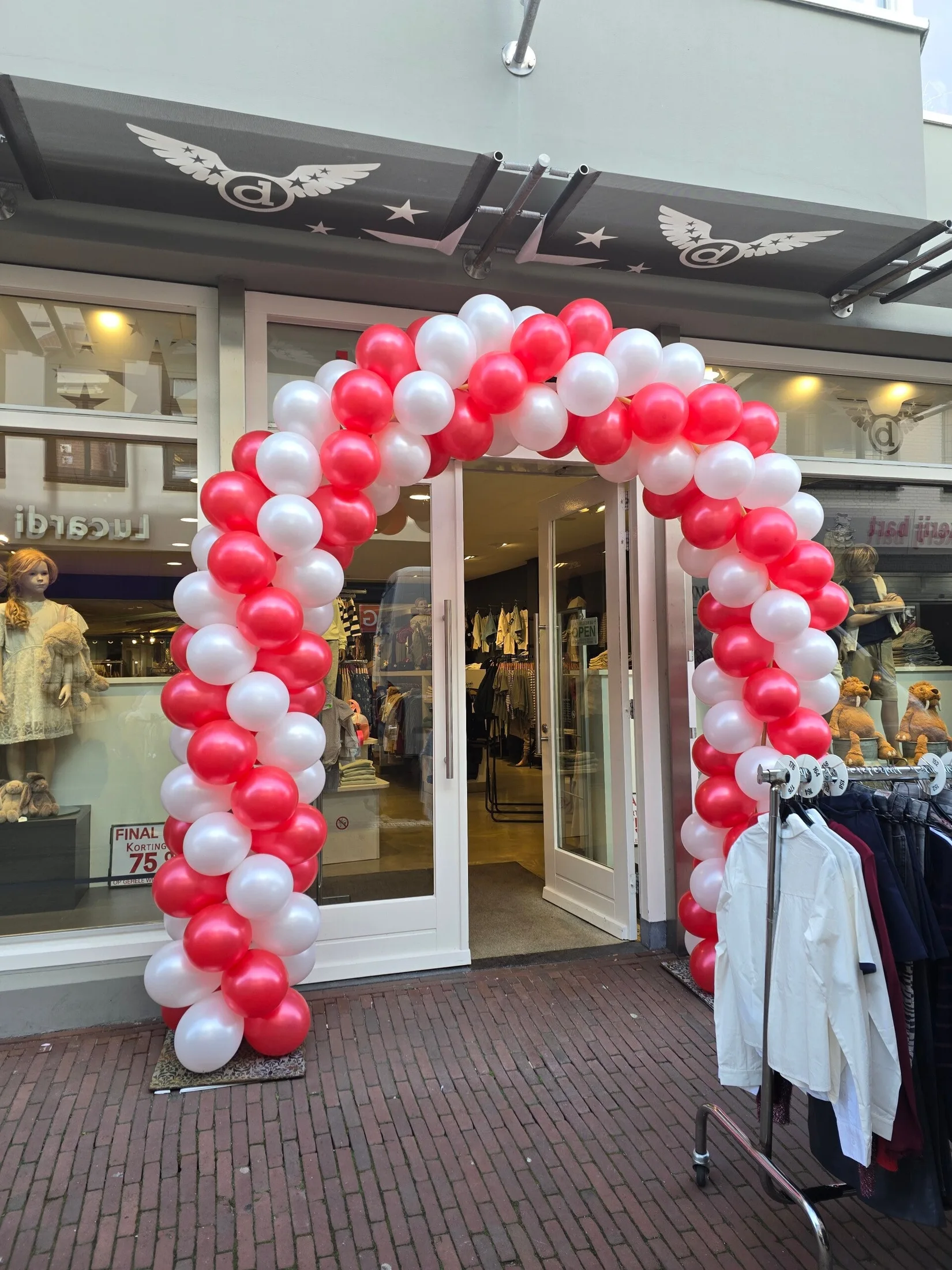 Rode en witte ballonnenboog van A&A Balloons bij een winkelopening